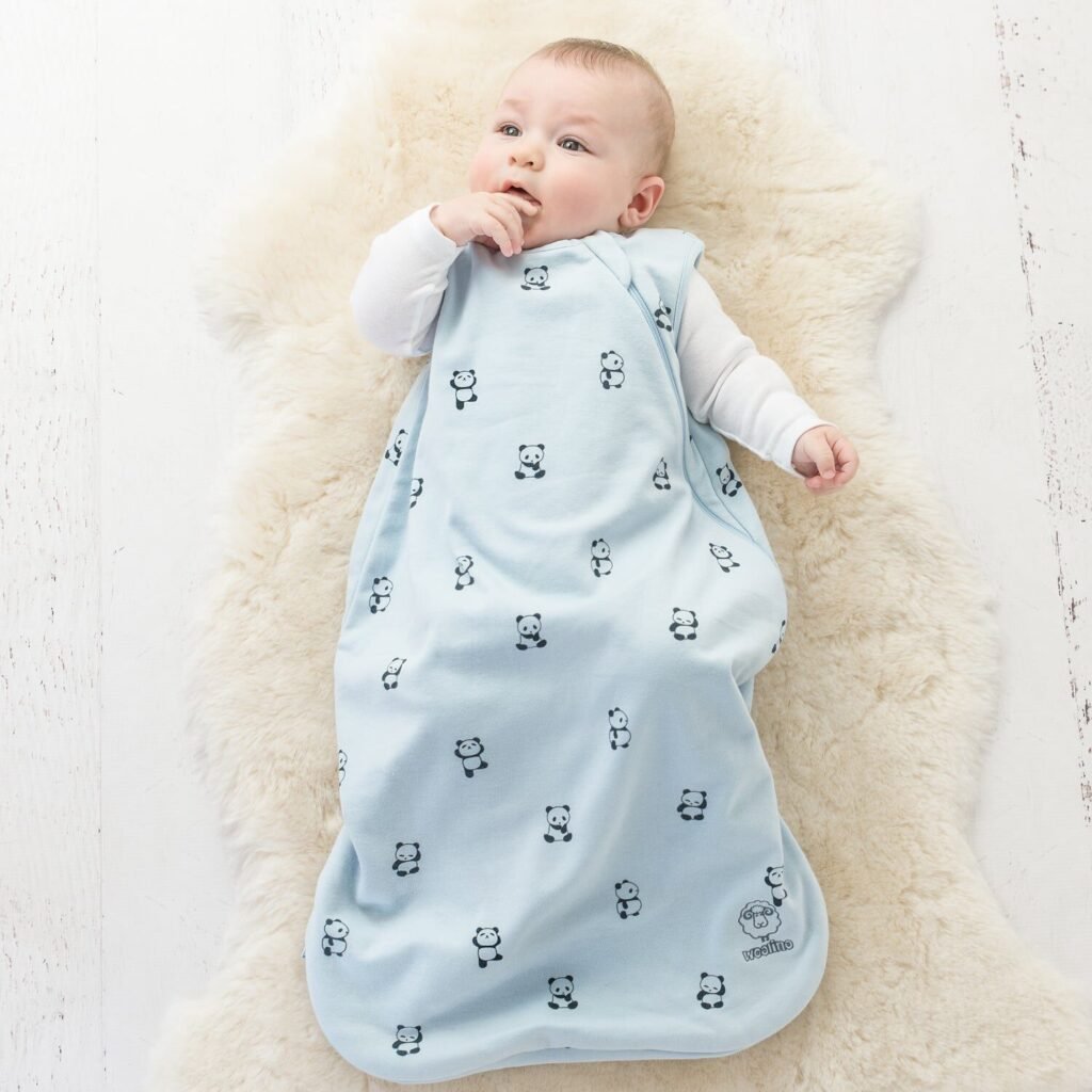 Baby lying on a lambskin rug wearing a panda print sleep bag