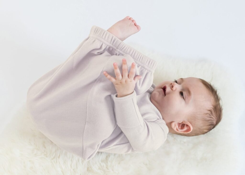 Happy baby discovering their feet while wearing a soft baby gown