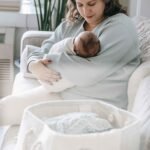 Mom holding her newborn next to a baby shower gift basket