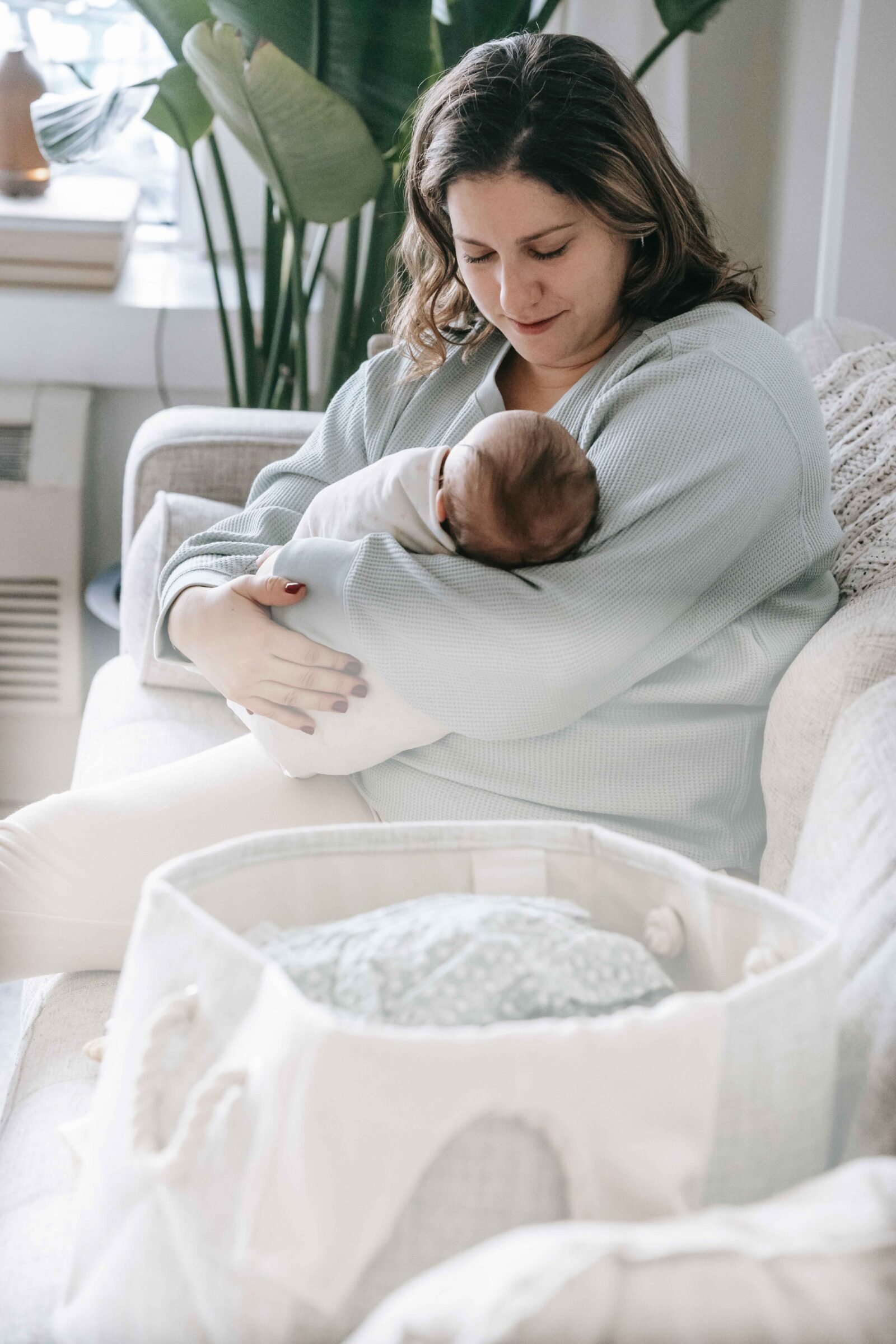 Mom holding her newborn next to a baby shower gift basket