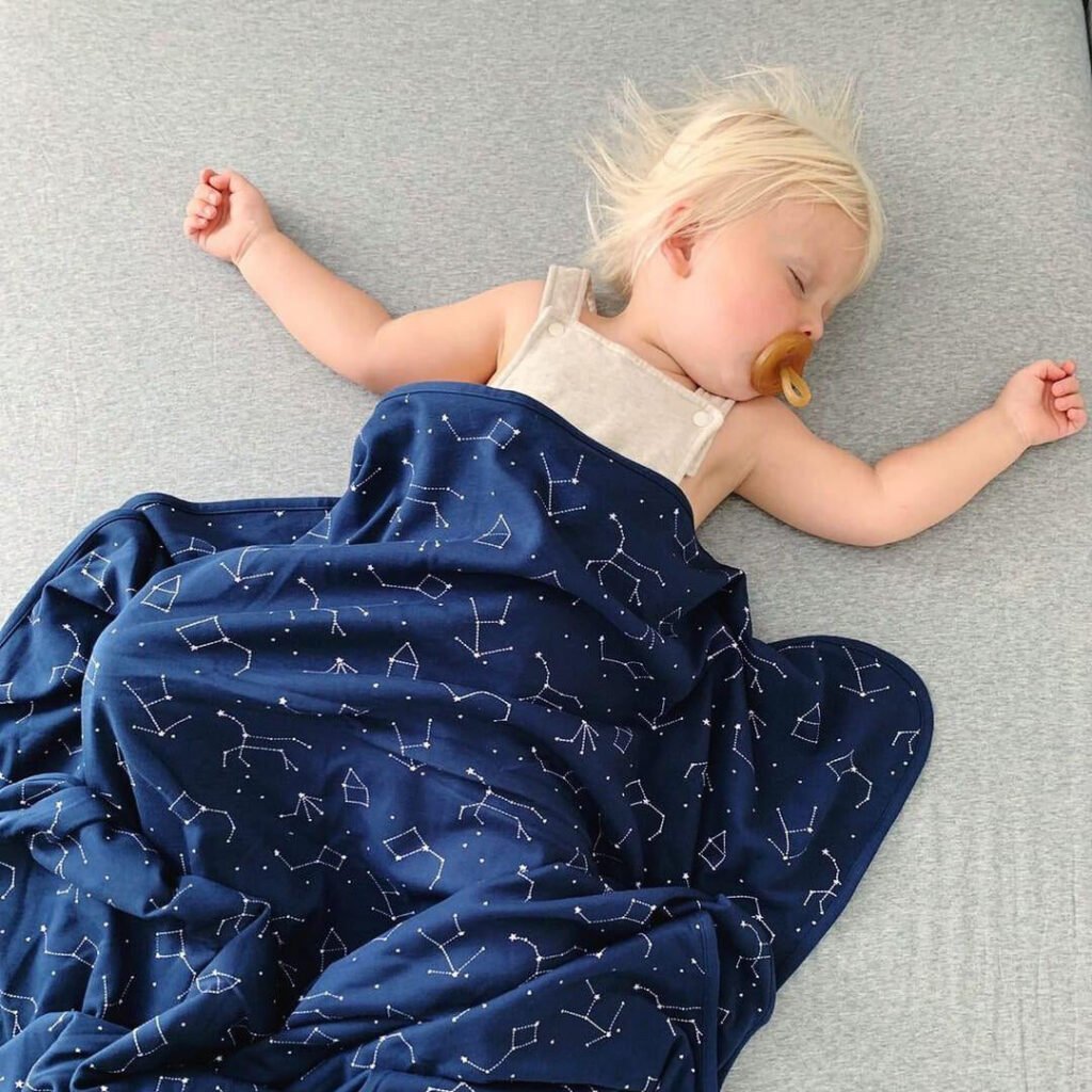 Toddler sleeping with a night sky print wool blanket